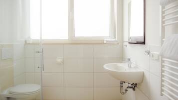 A bathroom with a toilet, a sink, a mirror, and a window.