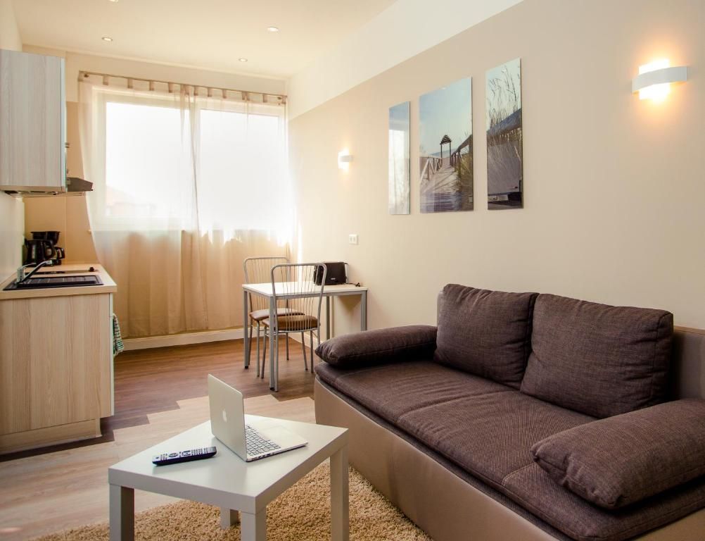 A modern living room with a sofa, a dining table, and a laptop on a small table.