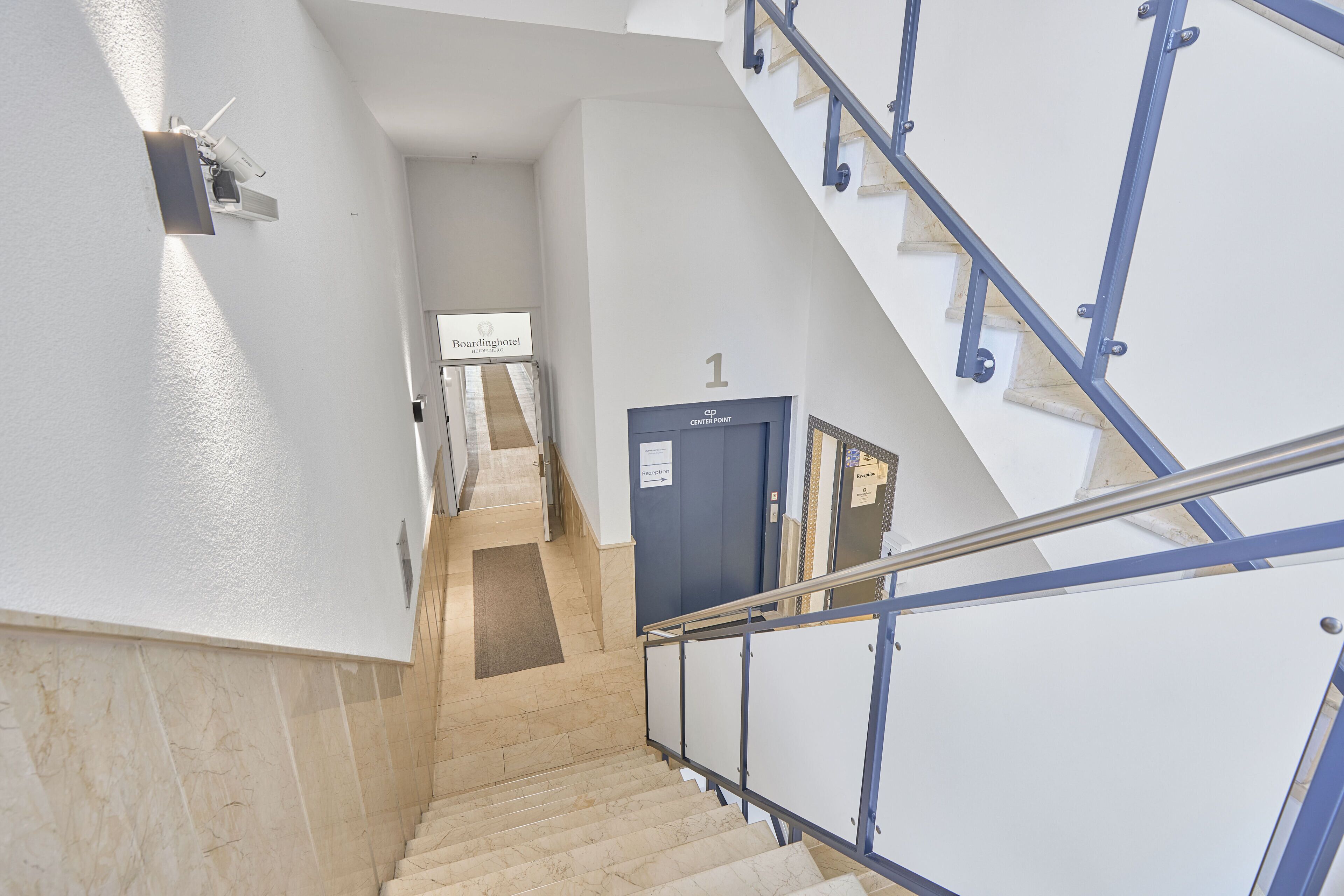 A staircase with a blue handrail leading to a door marked with the number 1.