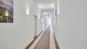 A long, narrow hallway with white walls, a patterned carpet, and framed pictures on the walls. - Boardinghotel Heidelberg (Heidelberg)