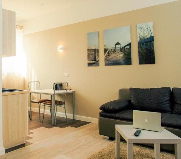 Un salon moderne comprenant un canapé, une table à manger avec des chaises et un coin cuisine avec un meuble de rangement.