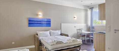 A bedroom with a bed, bedside table, and a view of the outside.