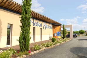 Un edificio con un letrero que dice "Hotel Albizia" y un área de estacionamiento al frente.