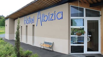 Ein Hotel namens "Hotel Albizia" mit Holzfassade, einer Bank vor der Tür und einer Tür mit dem Schild "TIREZ".