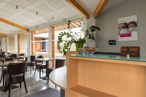 Un moderno vestíbulo de hotel con mostrador de recepción, zona de estar y grandes ventanales que permiten la entrada de luz natural.