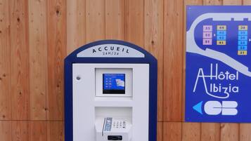 A hotel reception area with a ticket machine and a sign indicating room numbers and amenities.