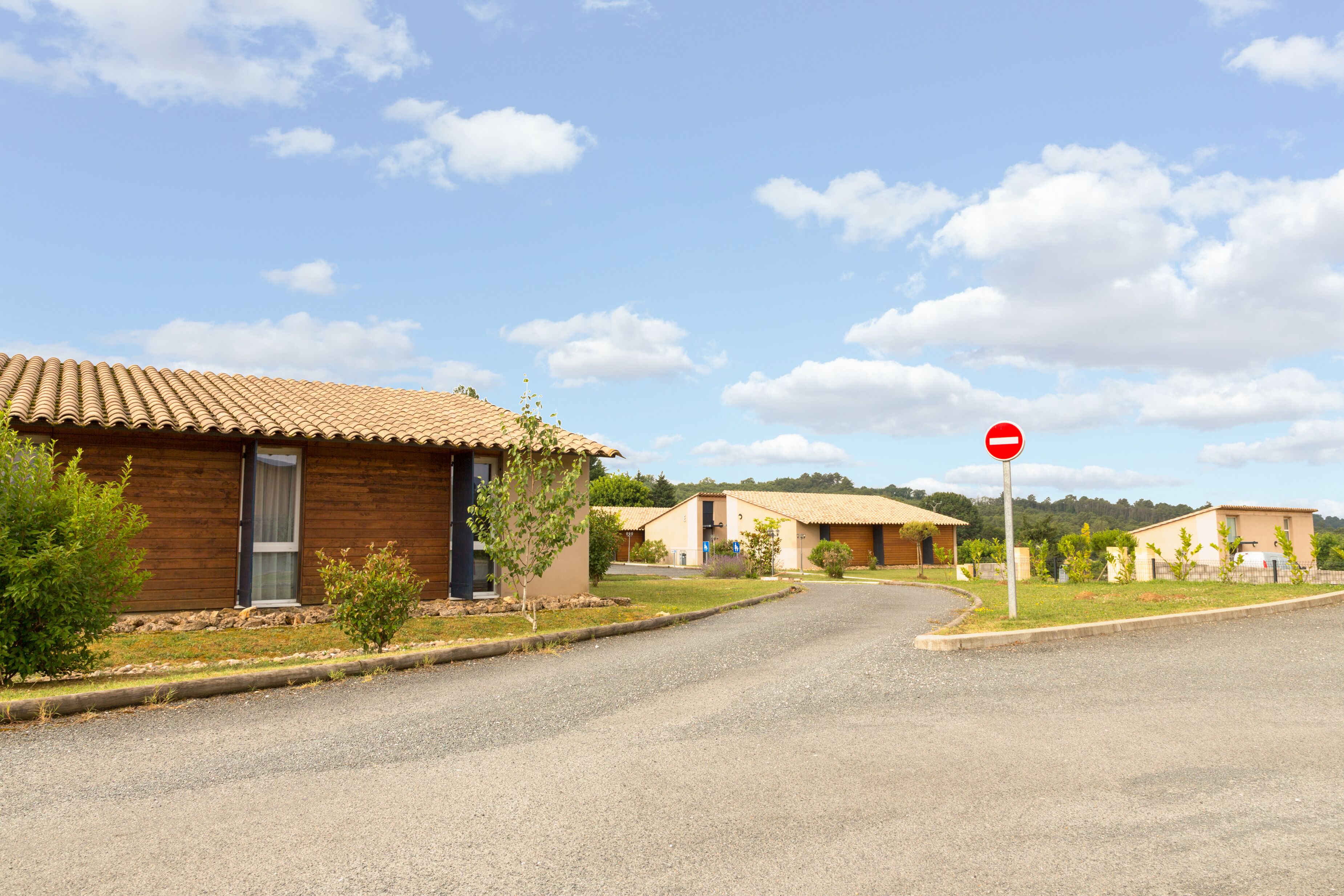 A residential street with houses, a stop sign, and a clear sky.