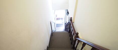 Un escalier avec des rampes en bois et un revêtement de sol en moquette, menant à un espace ouvert.