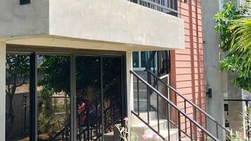 Een modern gebouw met balkon, trap en een tuin.