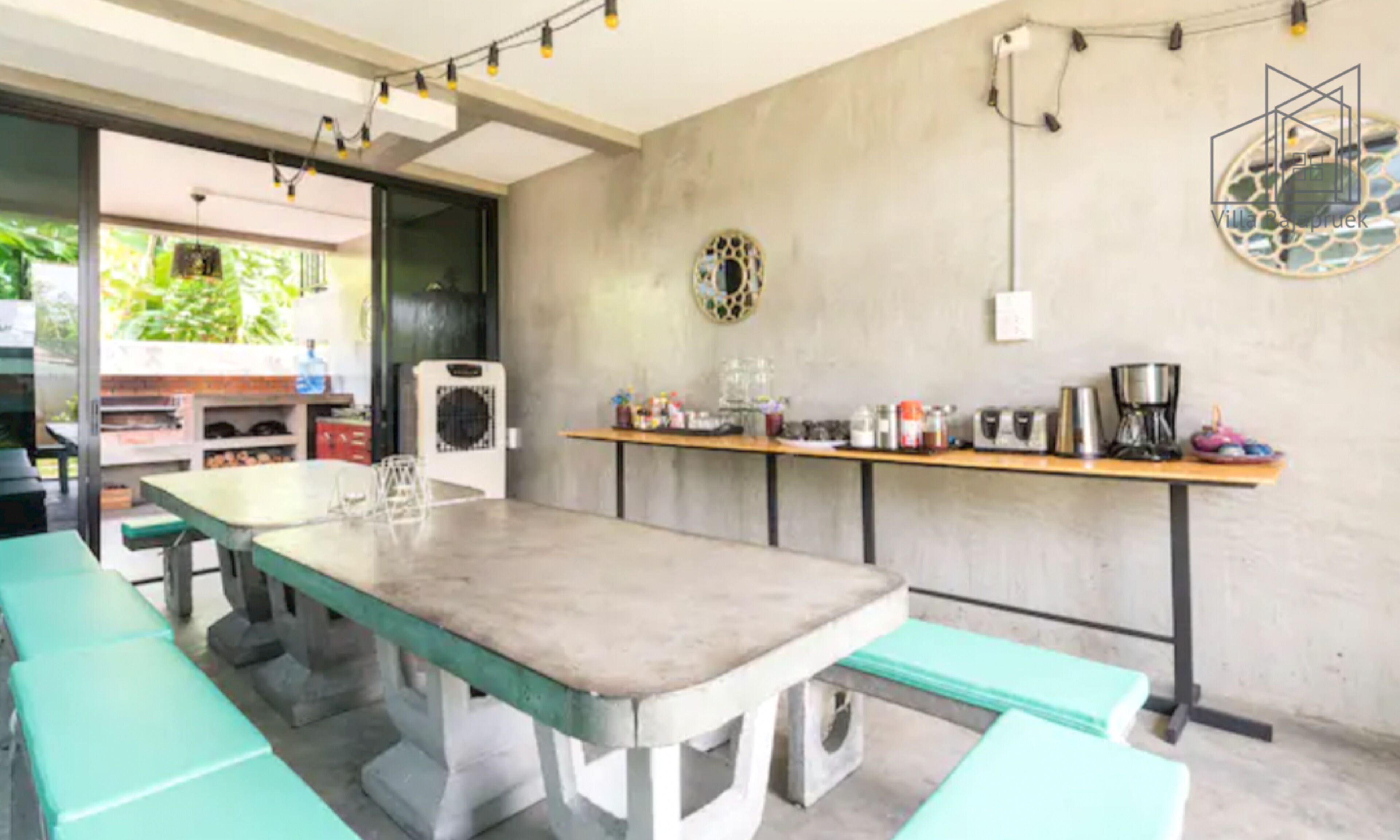 Una cocina con una mesa larga, bancos y varios electrodomésticos.