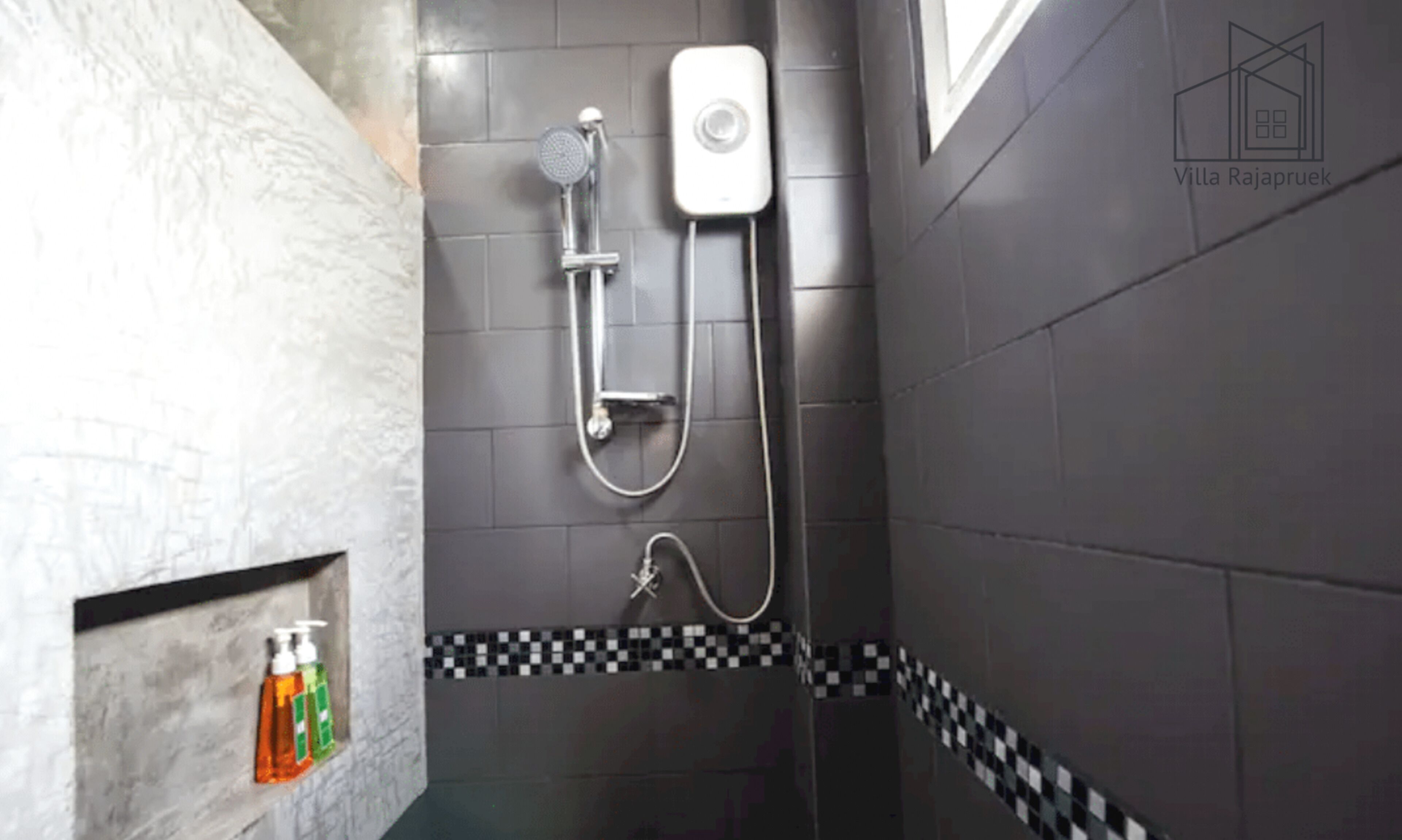 Un área de ducha con cabezal de ducha de mano, grifo empotrado en la pared y accesorio de ducha manual.