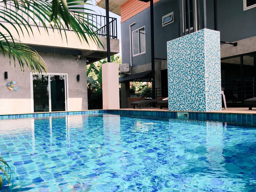 Una piscina con borde de azulejos, rodeada de edificios con balcones y una zona cubierta.