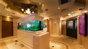 Een lobby met een groot aquarium, een receptiebalie en een bord met Hotel Luna.