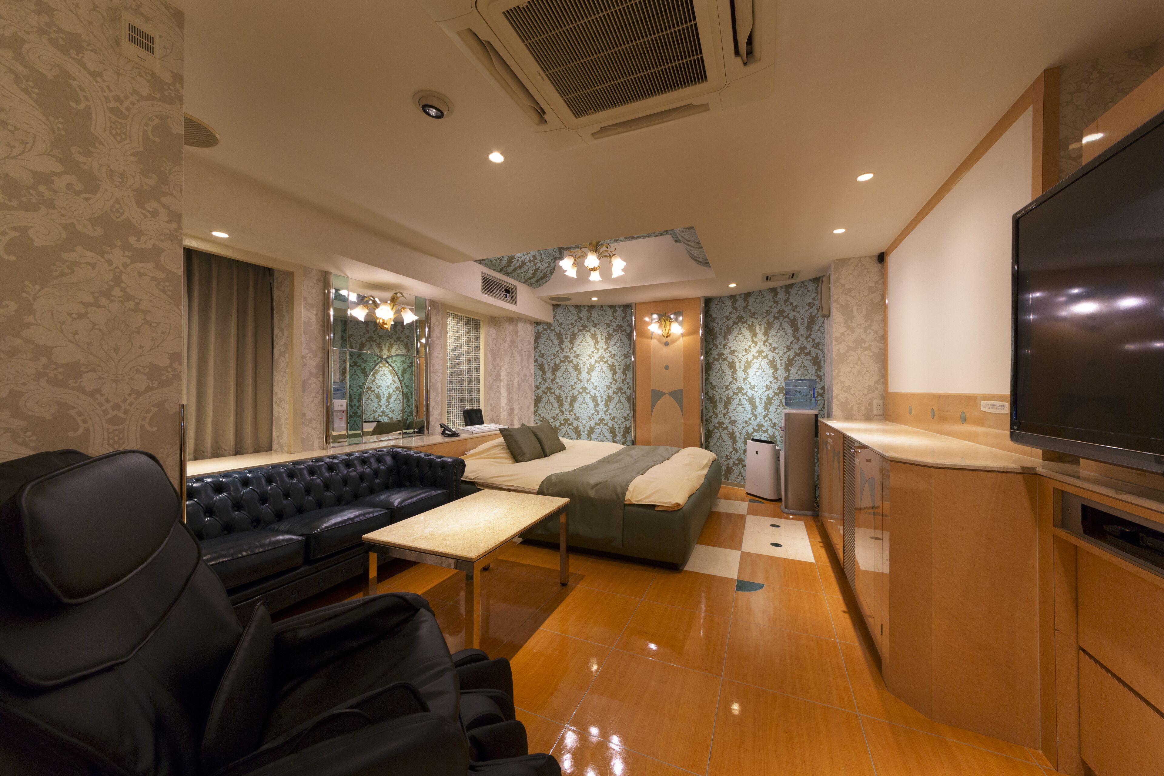 Een moderne hotelkamer met een bank, bed en kitchenette.