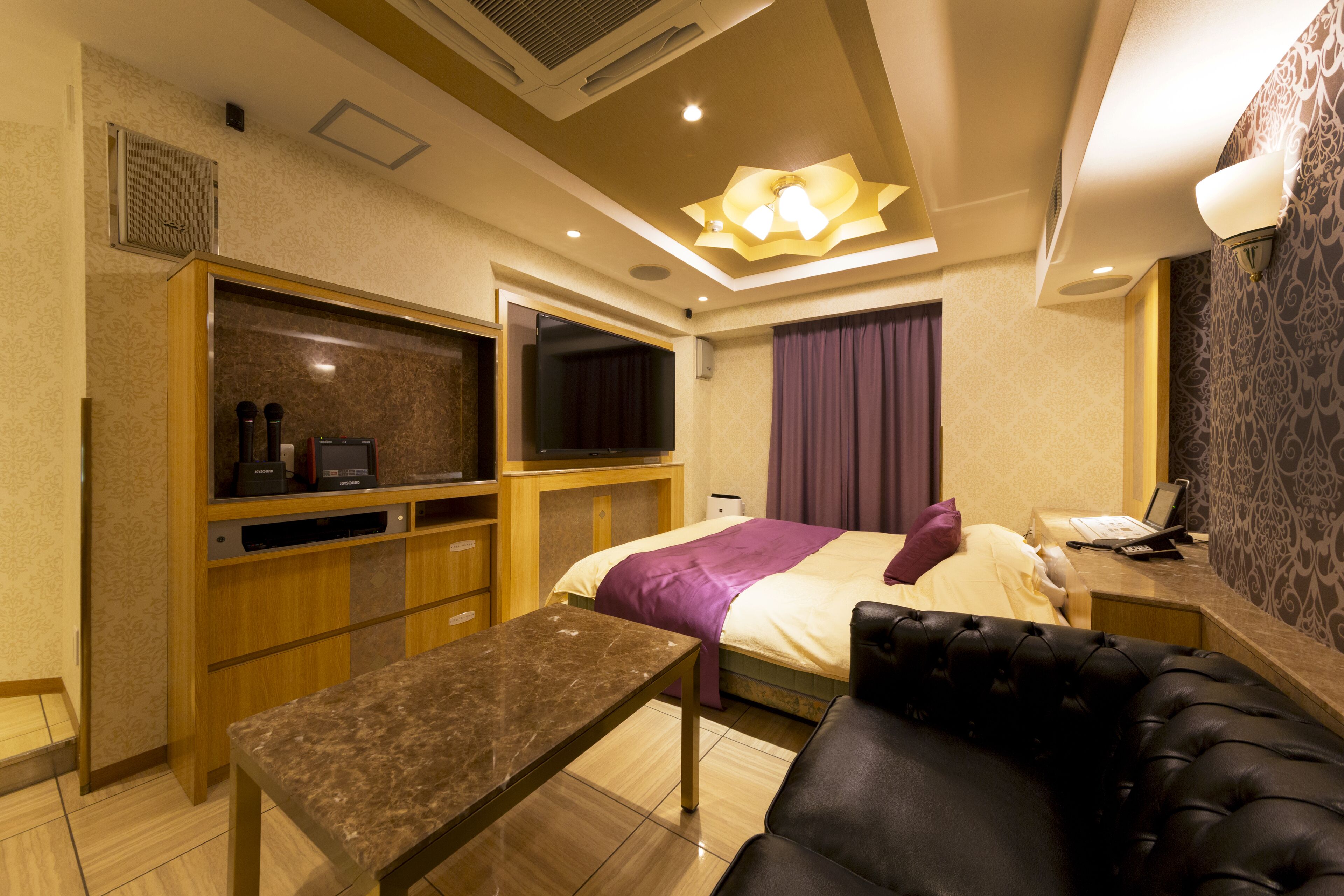 Ein Hotelzimmer mit Bett, Schreibtisch mit Computer, Fernseher und einer Sitzecke mit Sofa und Tisch.