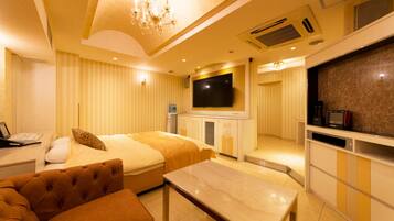 Une chambre d’hôtel équipée d’un lit, d’un canapé, d’une télévision, d’un bureau et d’un mini-bar.