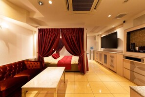 Una habitación de hotel con cama, sofá, televisión y kitchenette.