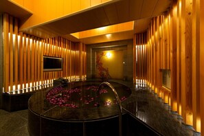 Un área de spa con un jacuzzi circular rodeado de paneles de madera y un televisor montado en la pared.