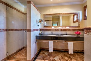 A bathroom with two sinks, a large mirror, and a shower area.