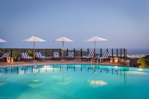 Una piscina al aire libre, sombrillas, sillones reclinables de piscina