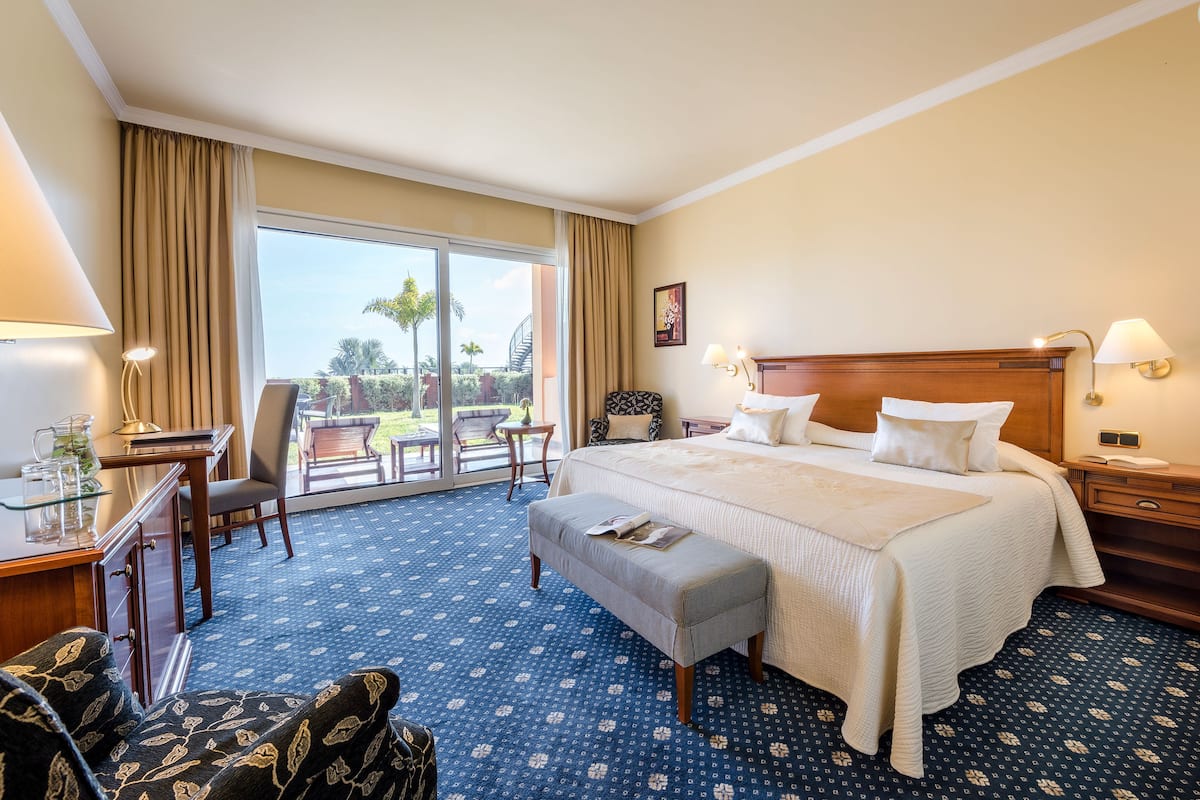 Habitación de hotel con una cama grande, un escritorio, una silla y vistas al exterior.