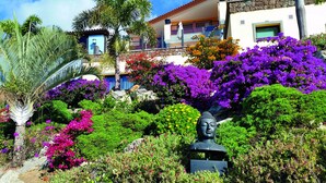 Un jardín con una estatua de Buda rodeada de flores y follaje exuberante.