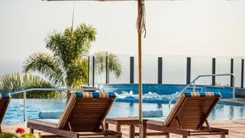 Een buitenzwembad, parasols bij het zwembad en ligstoelen