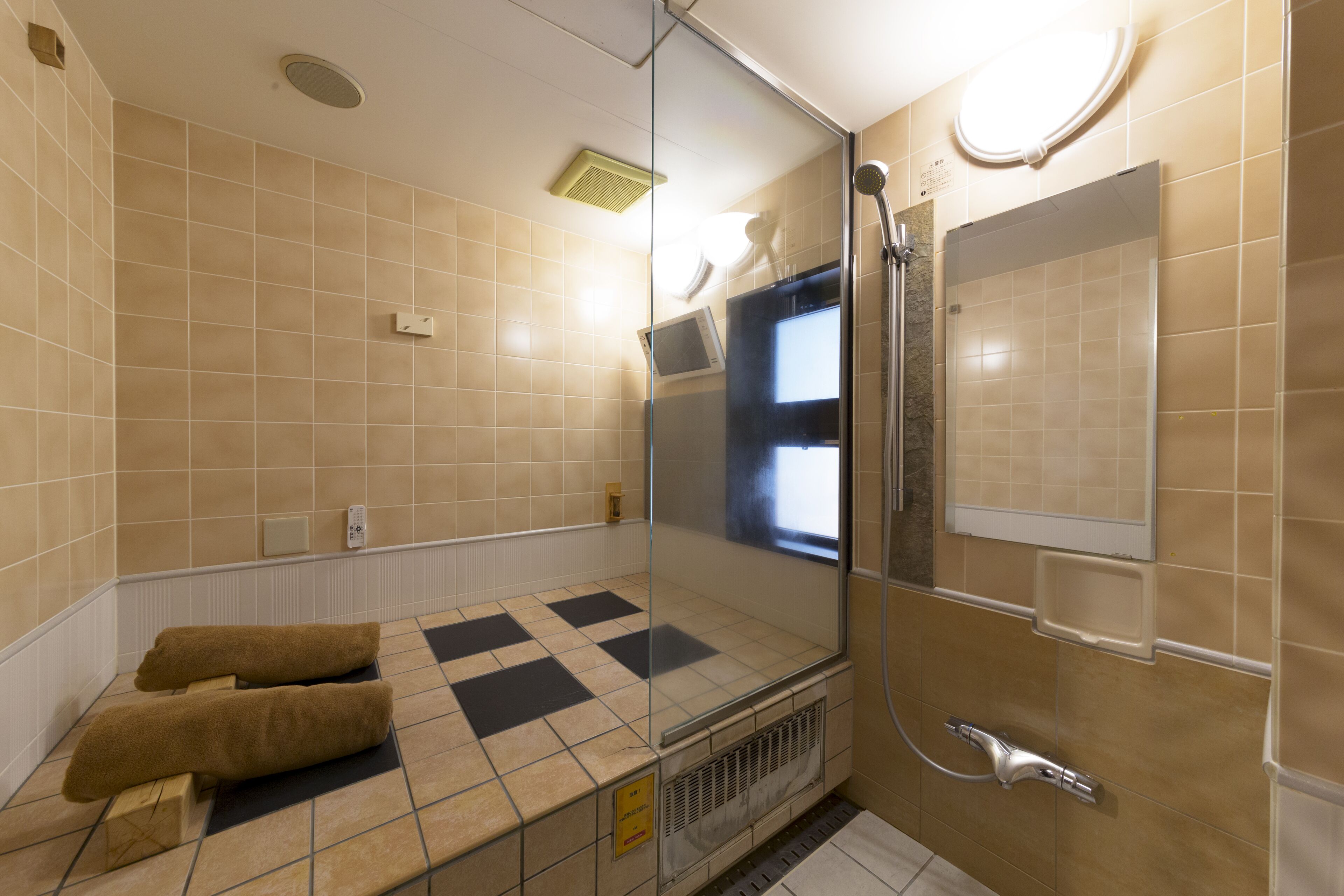 Moderni kylpyhuone, jossa on lasinen suihkuseinä, seinään upotettu wc-istuin ja pyyhekoukku.