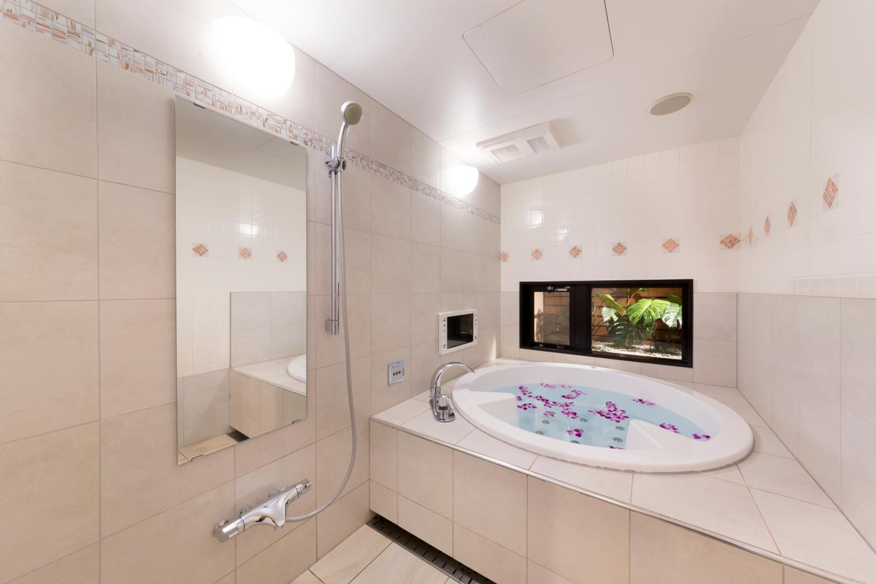 Une salle de bain moderne avec une grande baignoire, une douche et un miroir.