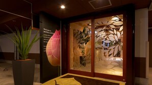 A hotel entrance with a large potted plant, a welcome sign, and a decorative glass door. - Hotel Lotus Nara - Adults Only (Nara)