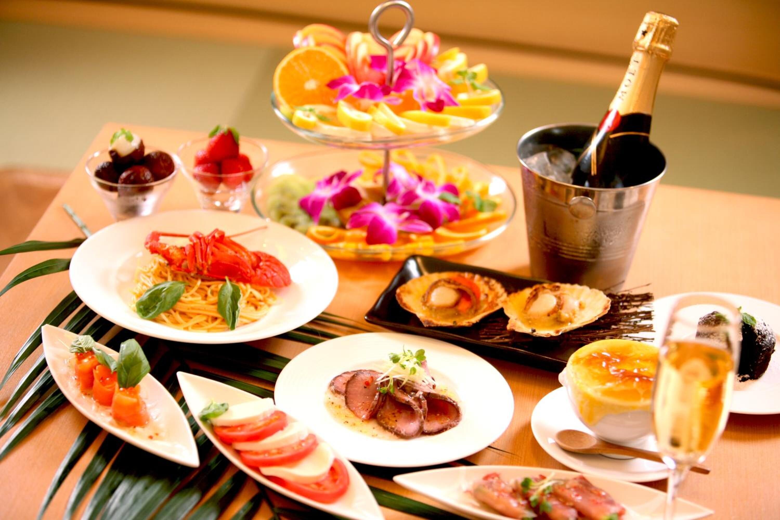 A table set with various dishes including seafood, a bottle of champagne, and a dessert.