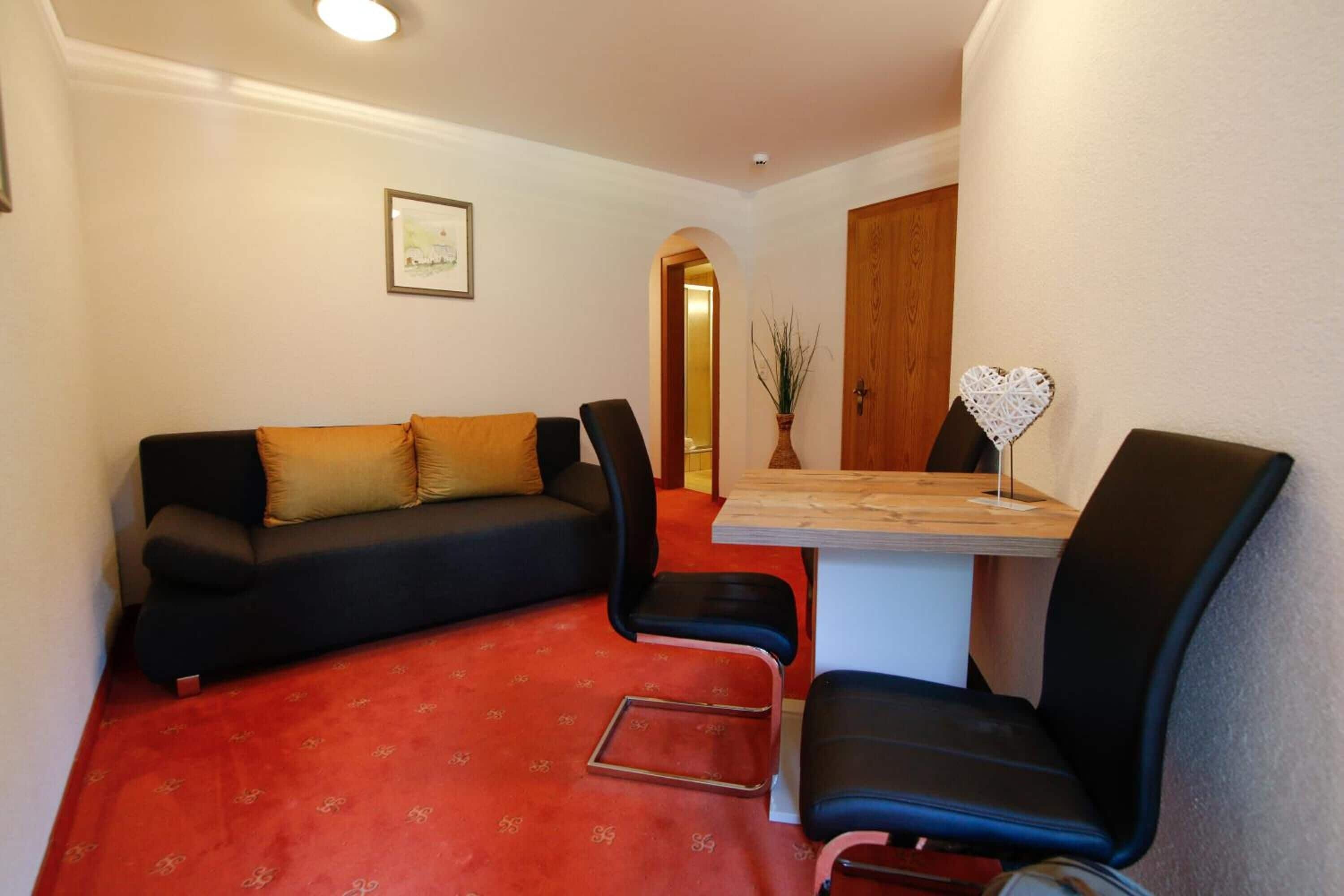 Un espacio habitable compacto con un sofá, dos sillones, una mesita y un adorno con forma de corazón en la pared.