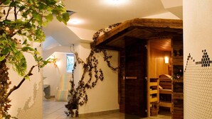 A hallway with tiled flooring, a wooden door, and a plant with hanging vines. - Hotel Tia Apart (Kaunertal)