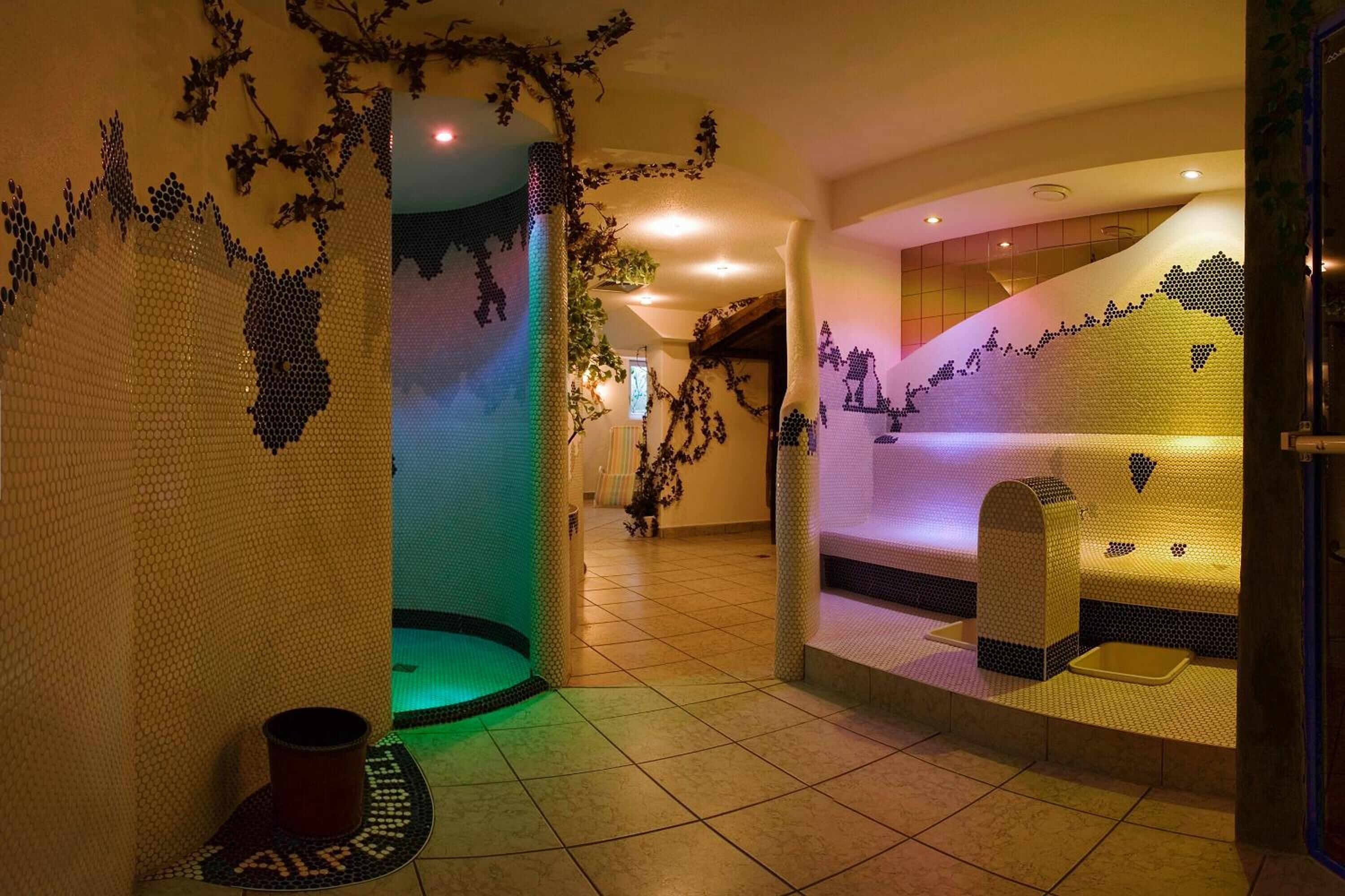 Uma área de spa com paredes em mosaico, espaço para sentar e piso ladrilhado.