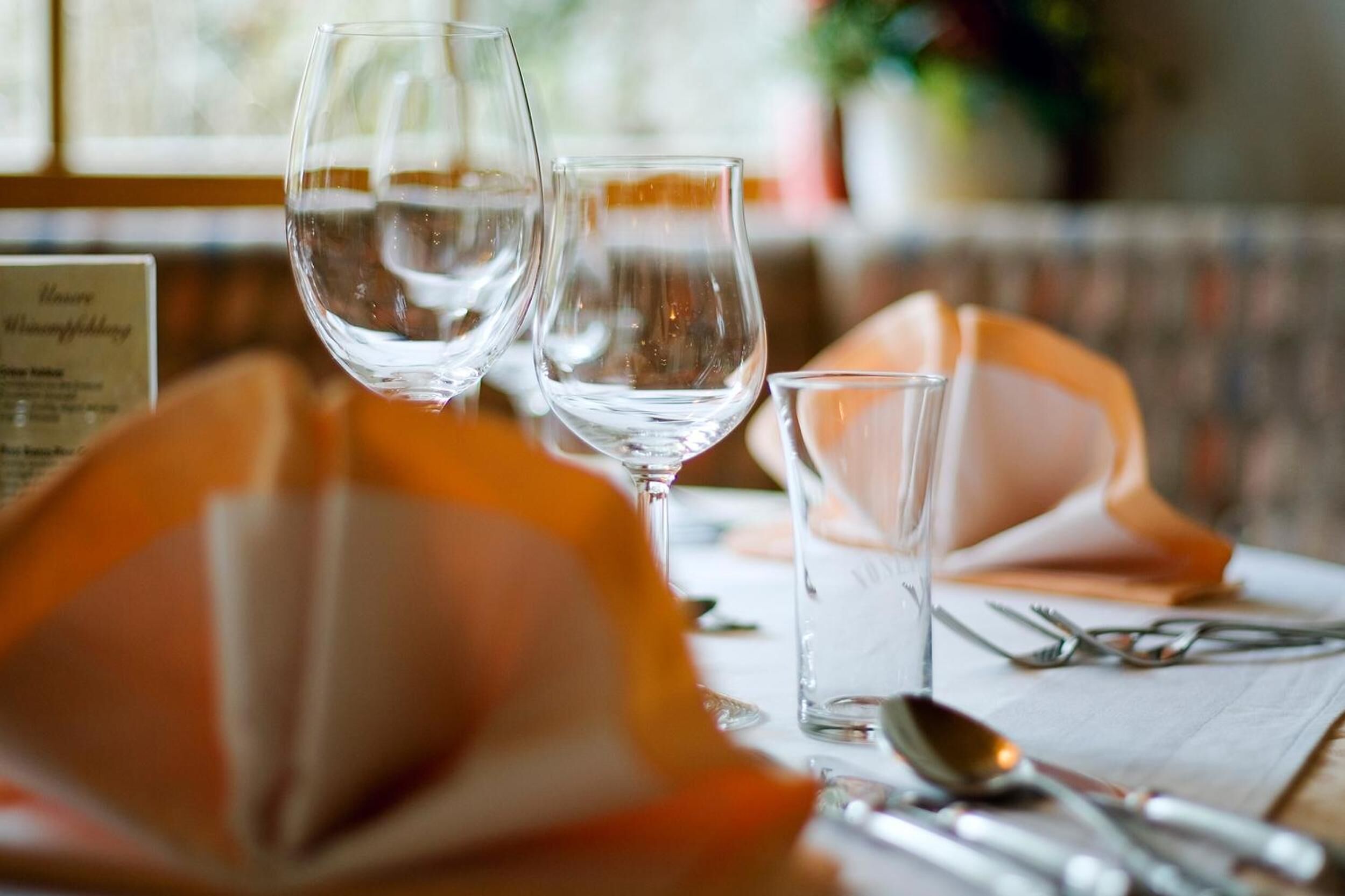 A table with two wine glasses, a small glass, and cutlery.