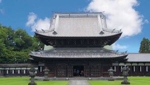 Un bâtiment traditionnel japonais, doté d’un toit en tuiles et d’une structure en bois.