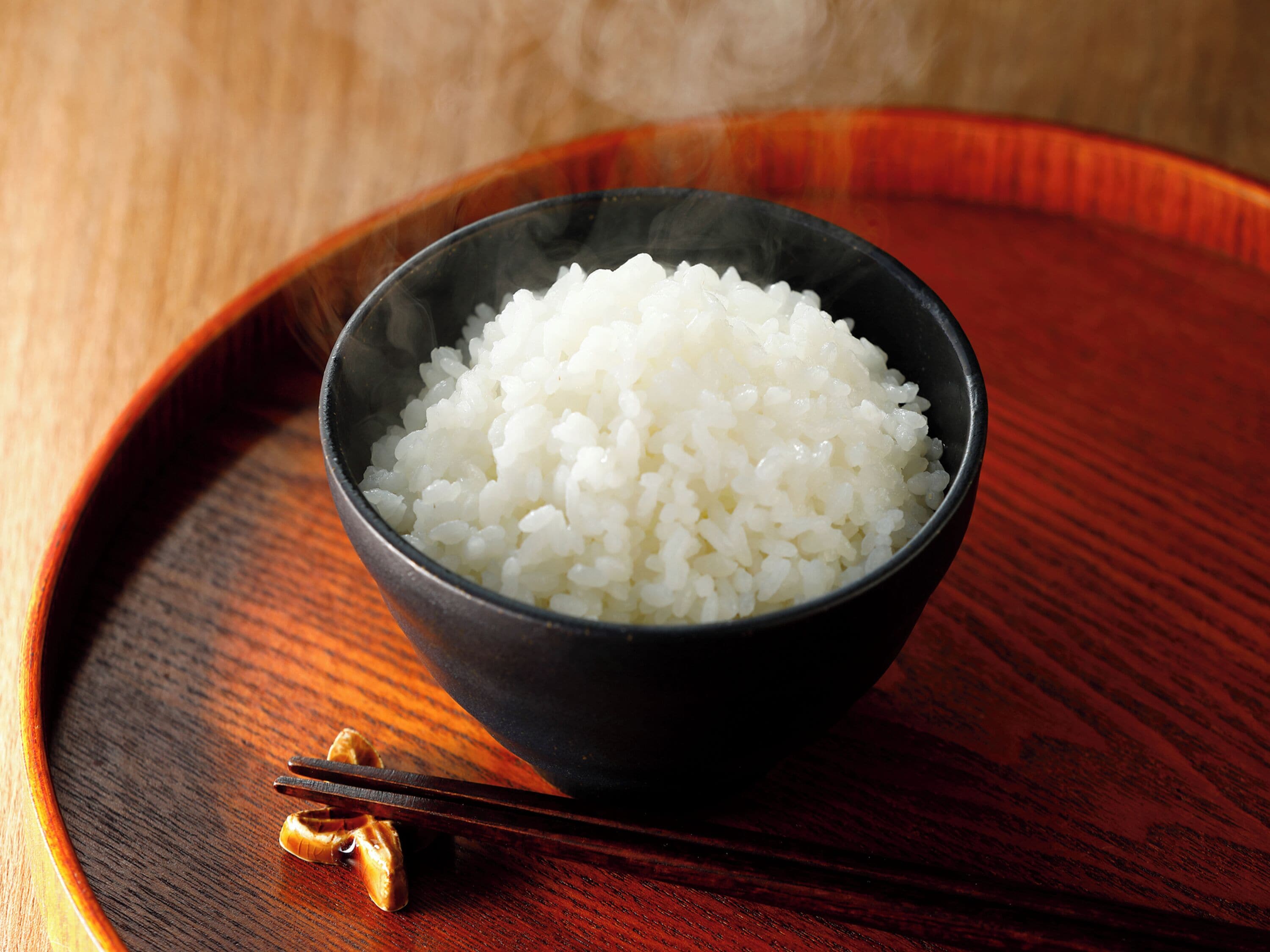 A bowl of white rice on a wooden tray.