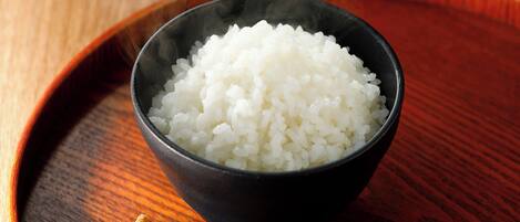 A bowl of white rice on a wooden tray.
