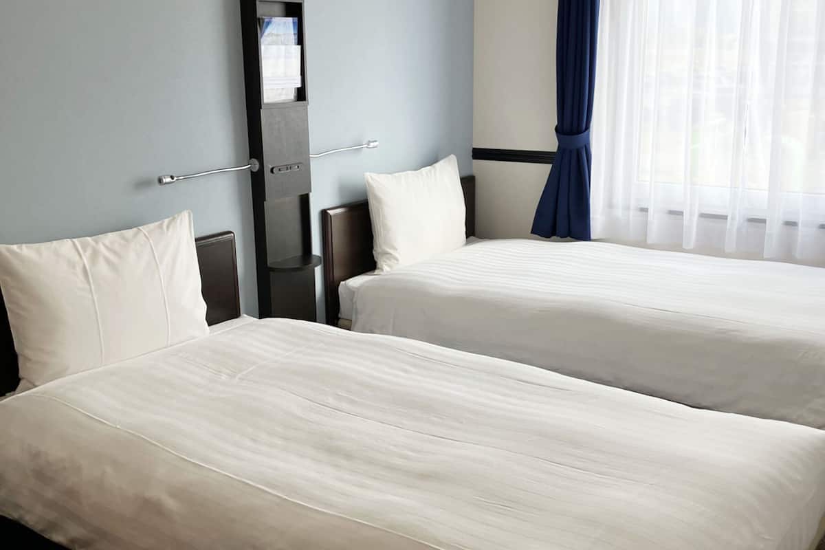 Une chambre d’hôtel avec deux lits, une table de chevet et un miroir.