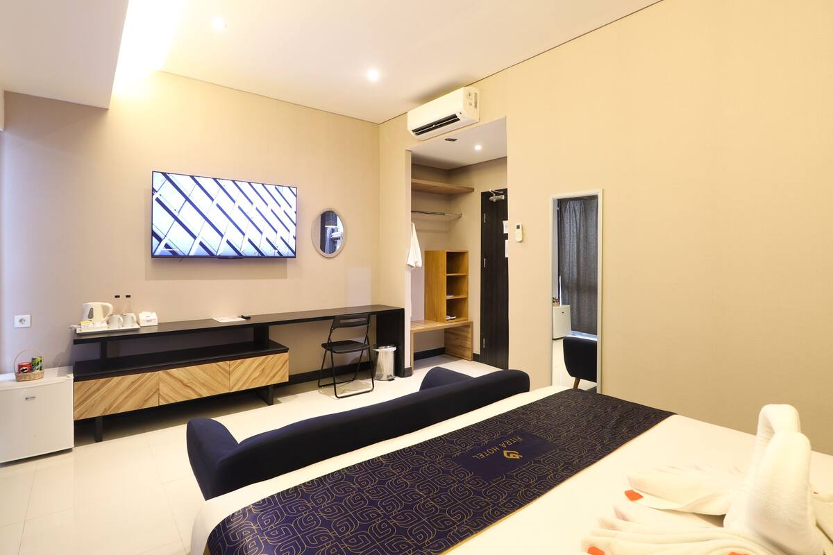 Una habitación de hotel moderna con cama, escritorio, silla, televisor y armario.