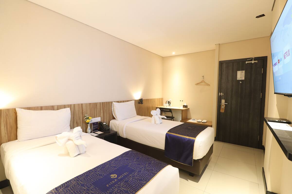 Una habitación de hotel con dos camas, un escritorio, un televisor y una puerta.