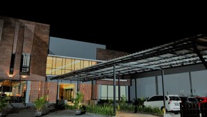 Un edificio moderno con fachada de ladrillo, ventanas amplias y zona de estacionamiento techada.