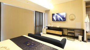 Una habitación de hotel moderna con una cama, televisión, escritorio y una pequeña zona de estar.