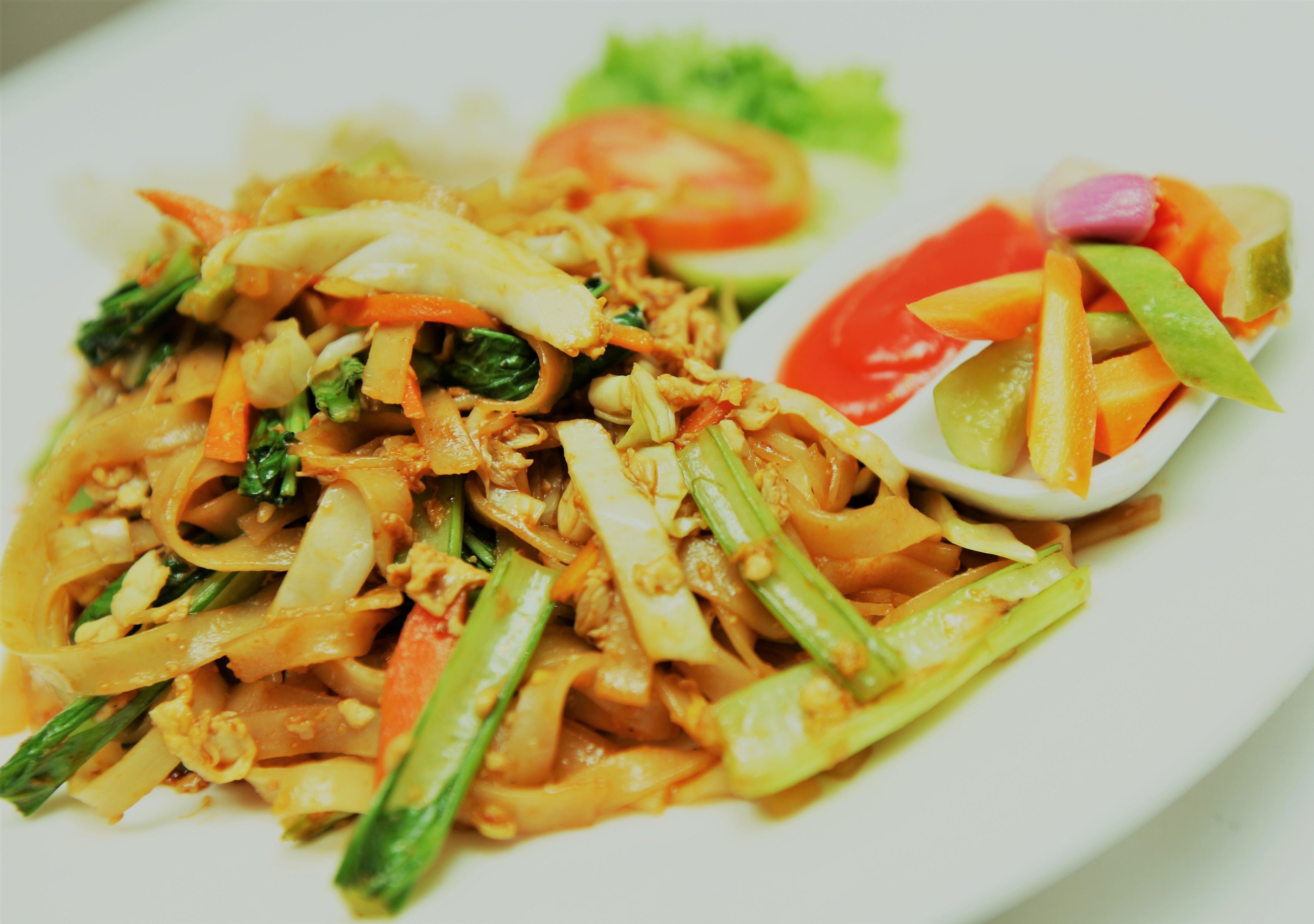 A plate of stir-fried vegetables with noodles and a side salad.