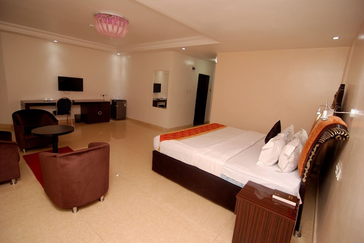Una habitación de hotel con cama, escritorio, silla y televisor.