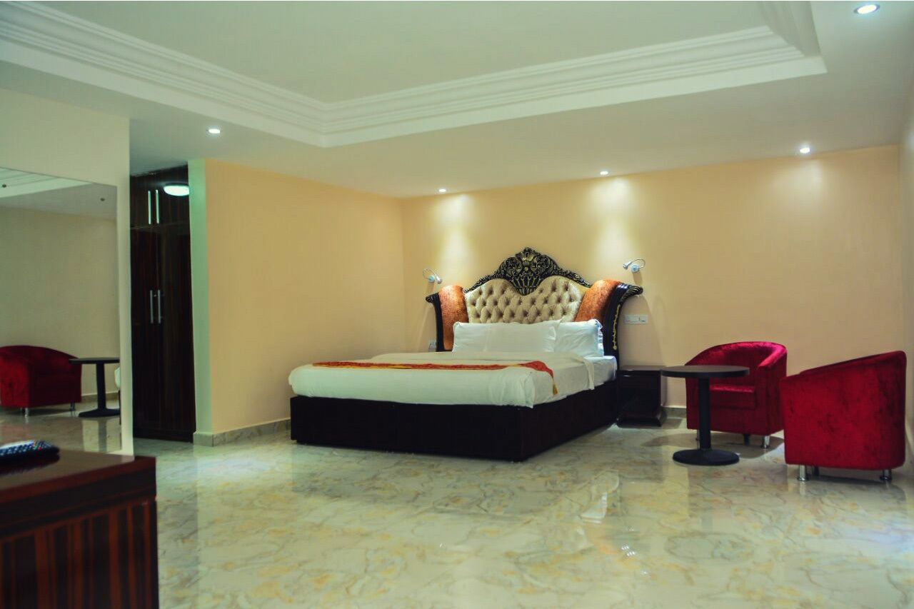 A spacious bedroom with a large bed, a red chair, and a small table.