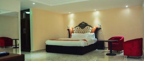 A spacious bedroom with a large bed, a red chair, and a small table.