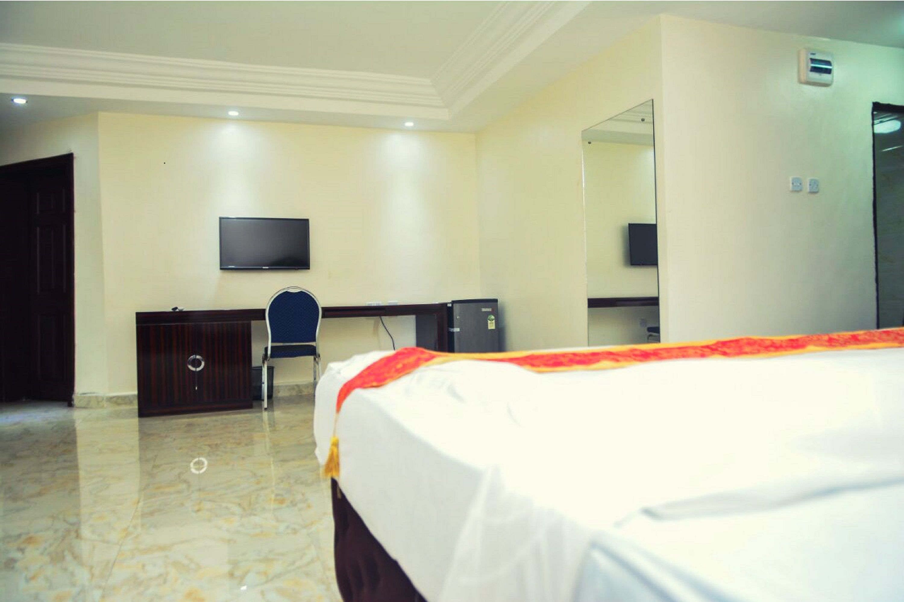 A hotel room with a bed, a desk, a chair, a television, and a wardrobe.