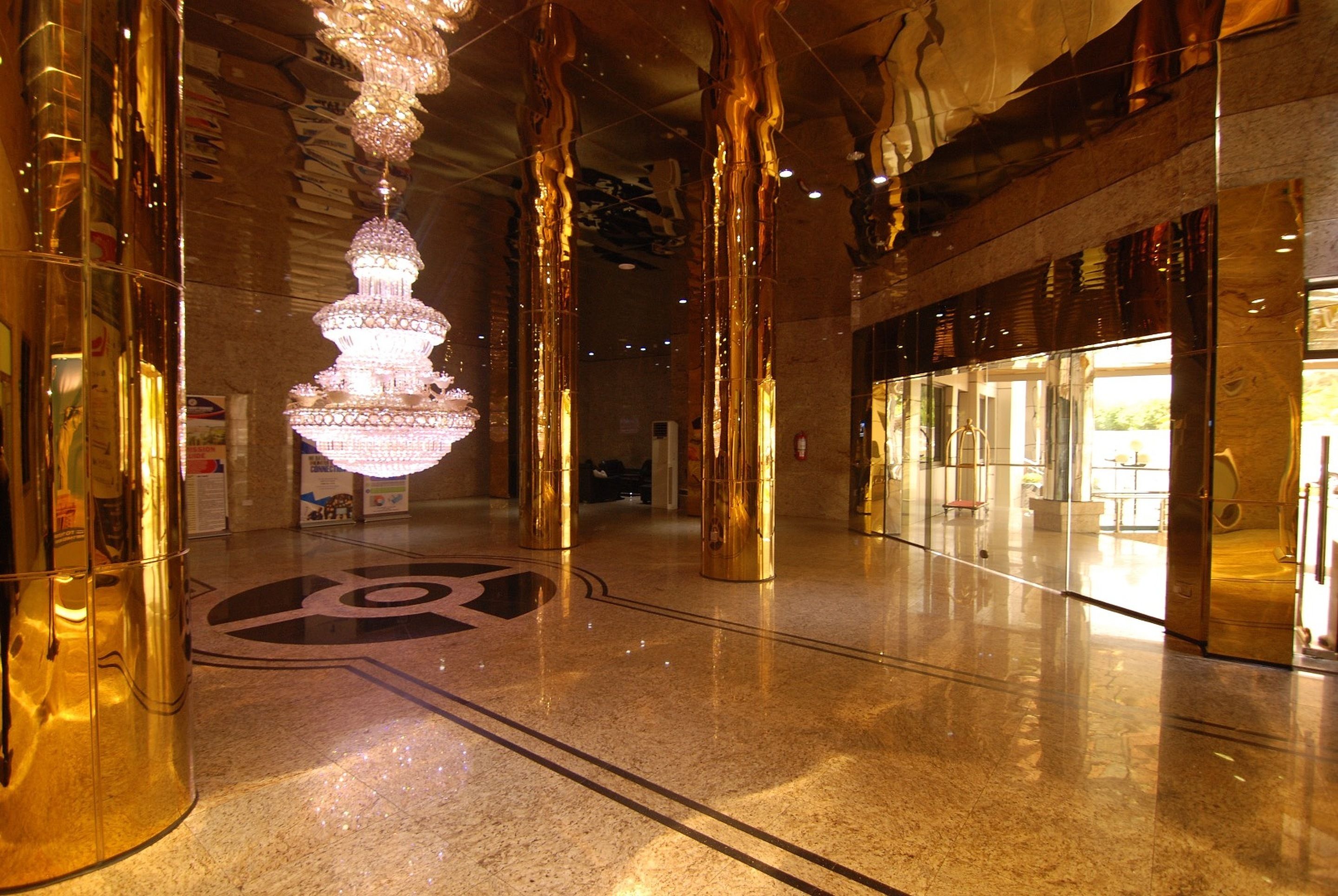 A spacious lobby with a large chandelier, polished marble floors, and a prominent circular logo.