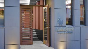A hotel entrance with a sign reading "LakeSpirit The Spirit of Hospitality" and a wooden slatted door leading to a staircase. - Lake Spirit Boutique Hotel & Spa (Ioannina)